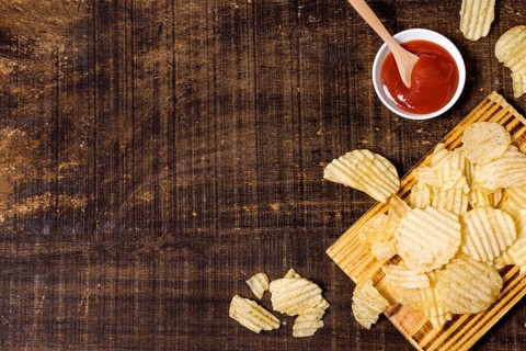 Top view potato chips with ketchup copy space