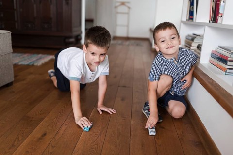 Two boys playing with car toys hardwood floor