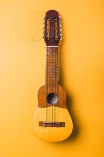 Ukulele with broken string yellow background