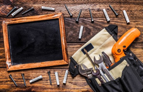 Various tools toolbag near blank slate bolts wooden background