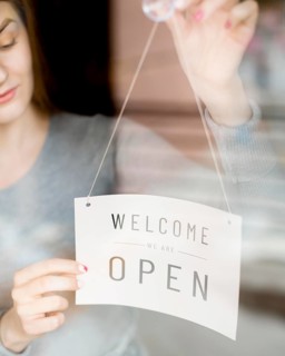 Woman putting open sign window coffee shop
