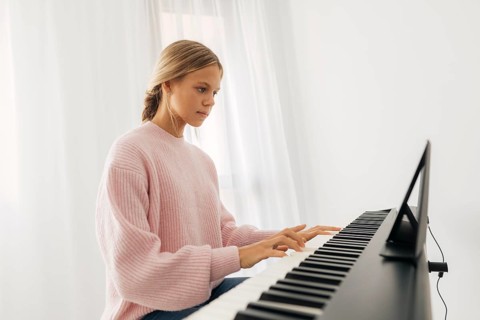 Young girl playing keyboard instrument home