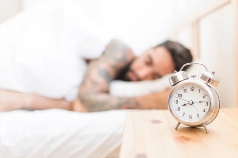 Alarm clock wooden desk with man sleeping background