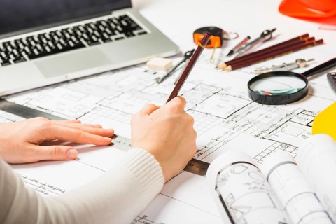 Architect drawing blueprint with pencil