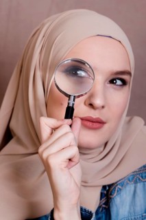Close up curious muslim woman looking through magnifying glass