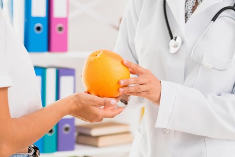 Close up doctor patient holding orange