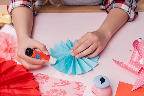 Close up female artist sticking blue origami paper fan