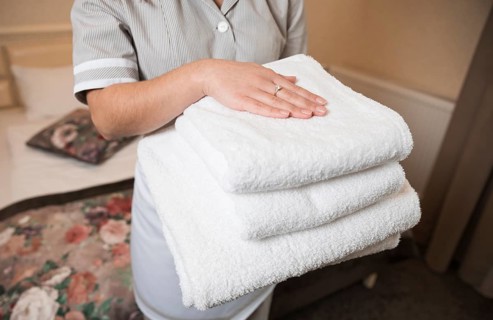 Close up female chambermaid holding clean soft folded towel hand