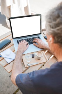 Close up man typing laptop with coffee water glass wooden table
