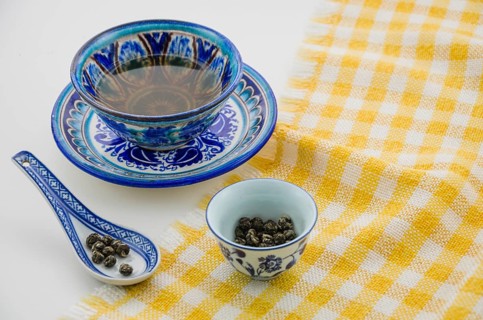 Close up oolong tea cup with spoon tablecloth against white background
