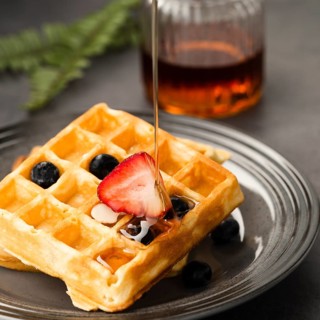 Close up view pouring maple syrup waffle