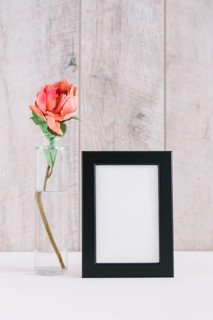 Colorful flower vase near blank picture frame table