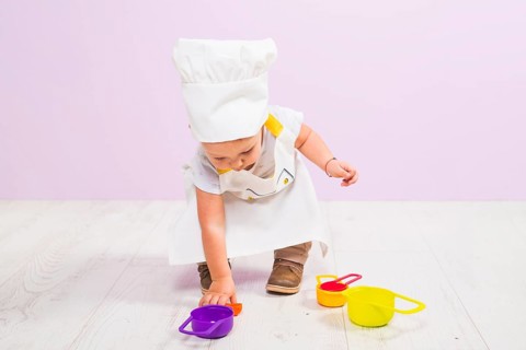 Cook child playing with toy dishes