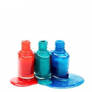 Different shades nail polish spilled around three opened bottles