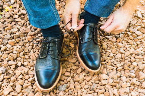 Elevated view man s foot pebble tying shoelace