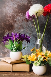 Fake flowers different type vase with wrapped gift boxes against grunge background