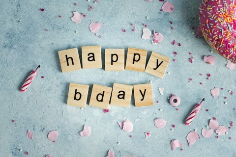 Flat lay happy birthday wish wooden letters with doughnut
