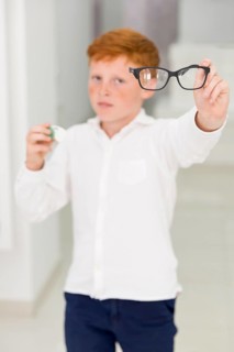 Freckle boy holding eyeglasses contact lenses container