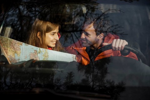 Front view couple with map inside car going road trip
