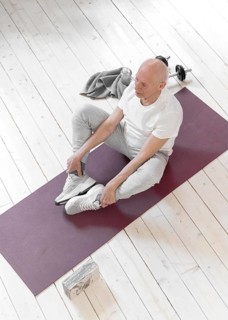 Full shot senior man sitting yoga mat