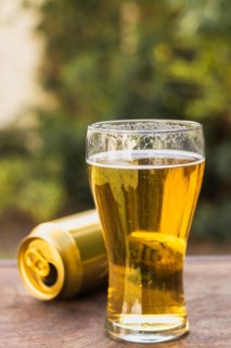 Glass with beer beside beer can