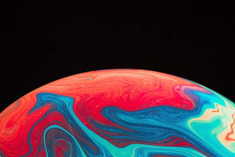 Gradient rippled multicolored soap bubble black background