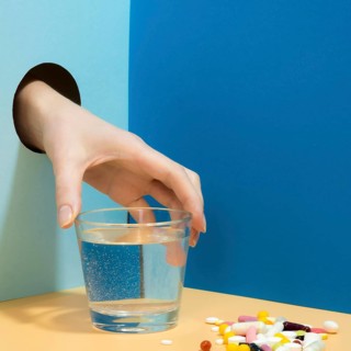 Hand grabbing glass water with pills it