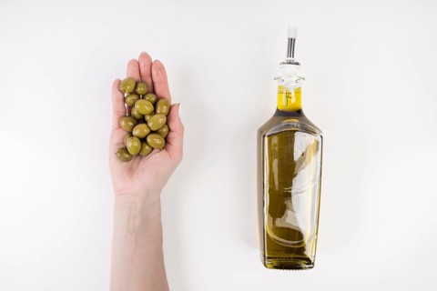 Hand holding olives bottle oil