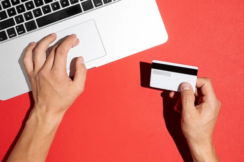 Hands using computer holding credit card