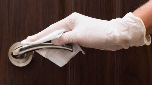 Hand with glove disinfecting door handle