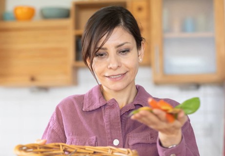 Woman in the kitchen disposes of organic waste in basket Environmental protection