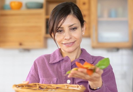 Woman in the kitchen disposes of organic waste in basket Environmental protection