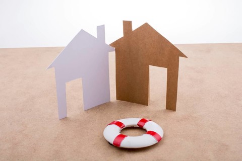 Little model life preserver and paper houses on a brown background