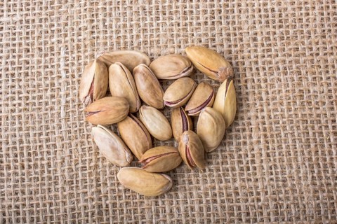 Pistachios form a heart shape on canvas background