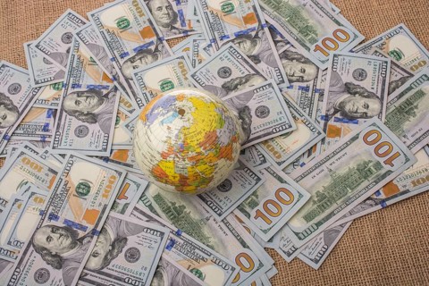 Model globe is placed on spread US dollar banknotes
