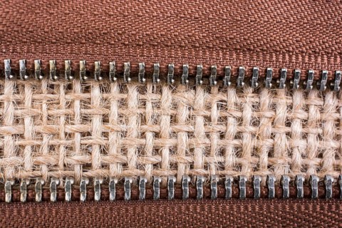 Parts of the brown color zipper on linen canvas background