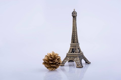 Little model Eiffel Tower and pine coneon a white background