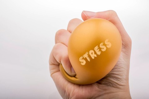 Squeezing yellow balloon with hand on a white background