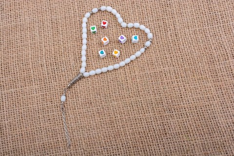 Heart shaped cubes in hand by inside a praying beads