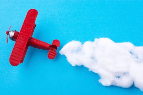 Retro styled little red model airplane in sky