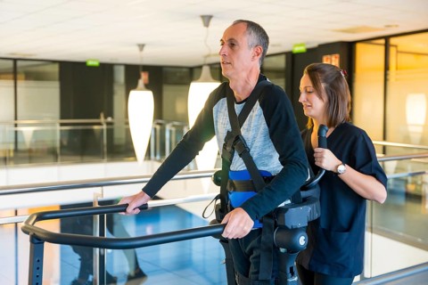 Mechanical exoskeleton. Female physiotherapy doctor helping disabled person with robotic skeleton to walk. Futuristic rehabilitation