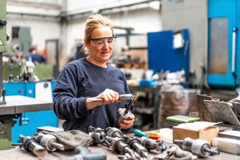 Female factory worker operator working in numerical control sector measuring drill bits
