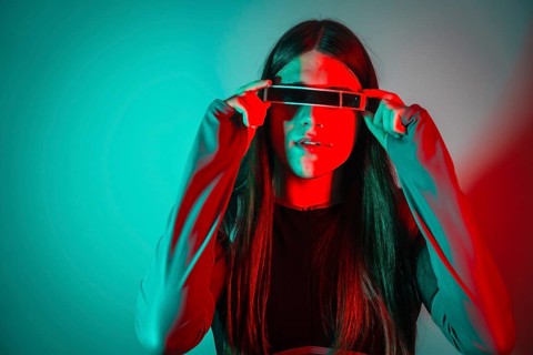 Futuristic studio portrait with neon lights of a transgender person with long hair using smart googles