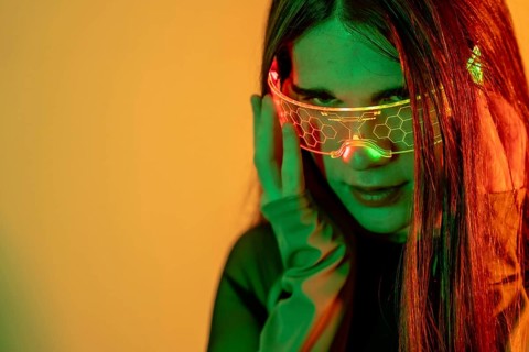 Futuristic studio portrait with neon lights of the eye contact of a transgender futuristic person using smart goggles