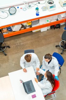 Vertical photo with top view of a team of biologist working with samples using laptop