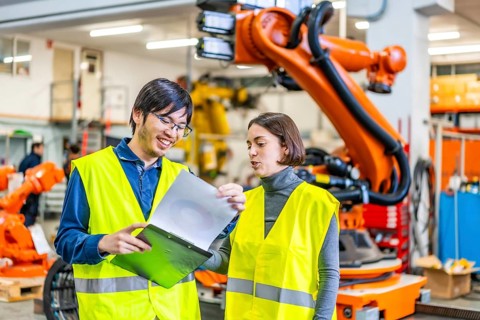Male and female multi-ethnic engineers reading data while working in a robotic industry