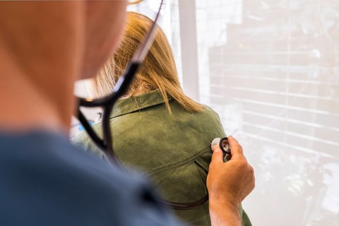 Doctor using stethoscope on his patient's back to listening to lungs for breathing problem. Copy space