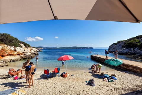 Small family beach Cala Dragunara with tourists