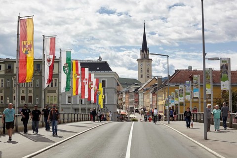 Flags on the Drau bridge with parish church