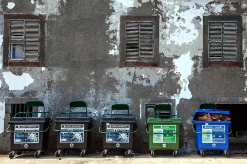 Dustbin in front of an old house wall